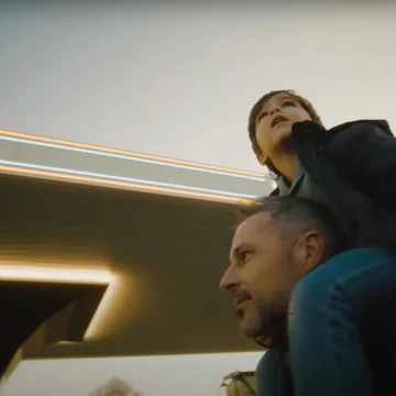 Un bambino in braccio al padre in una stazione di ricarica Free To X