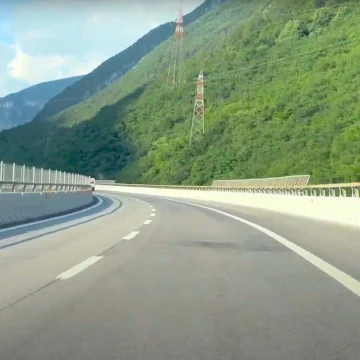 Highway running alongside wooded mountains